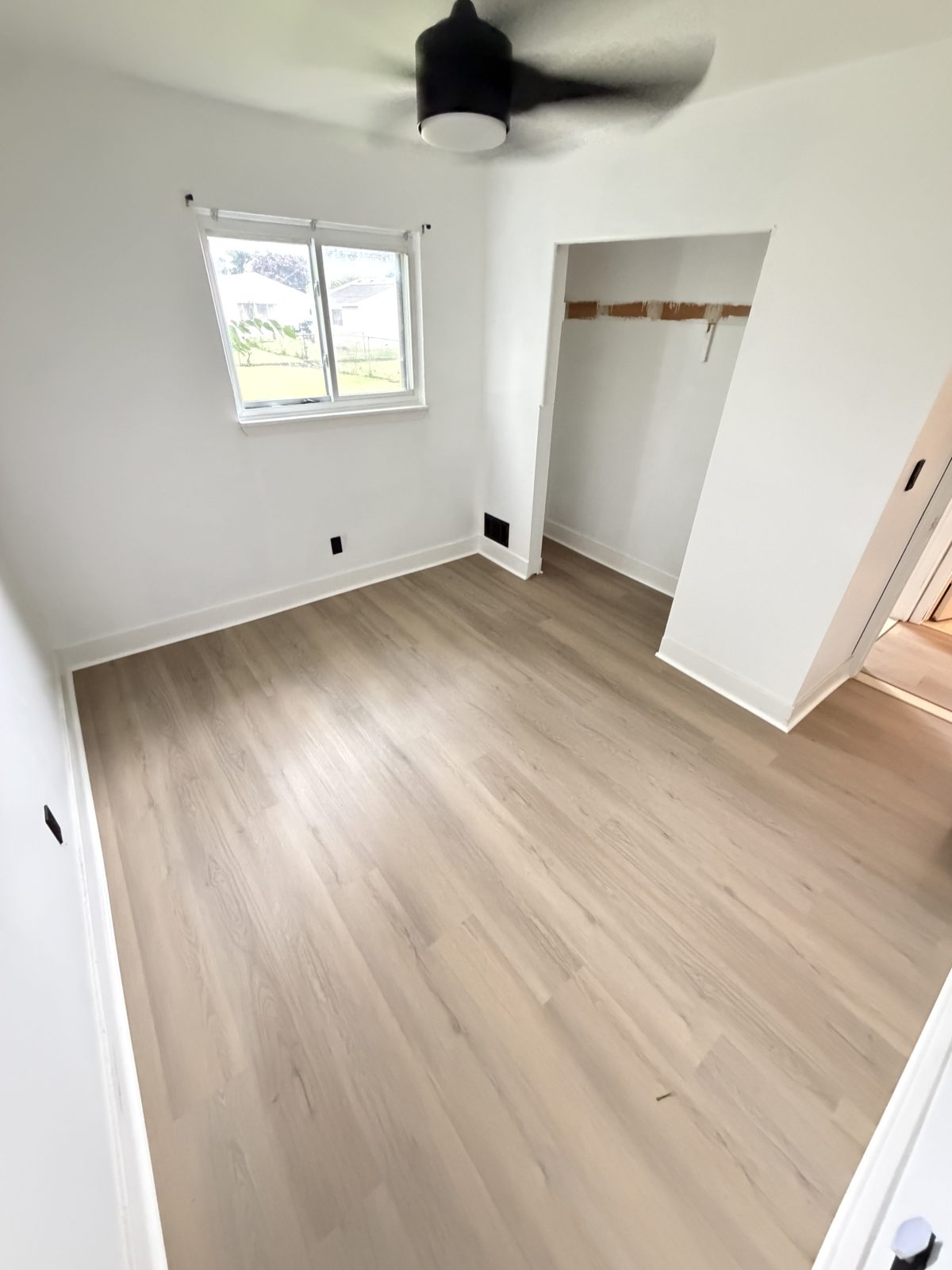 Small bedroom with light oak-look luxury vinyl plank flooring