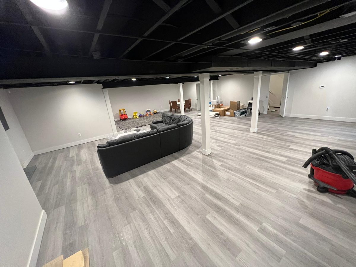 Large open finished basement with light grey wood-look plank flooring