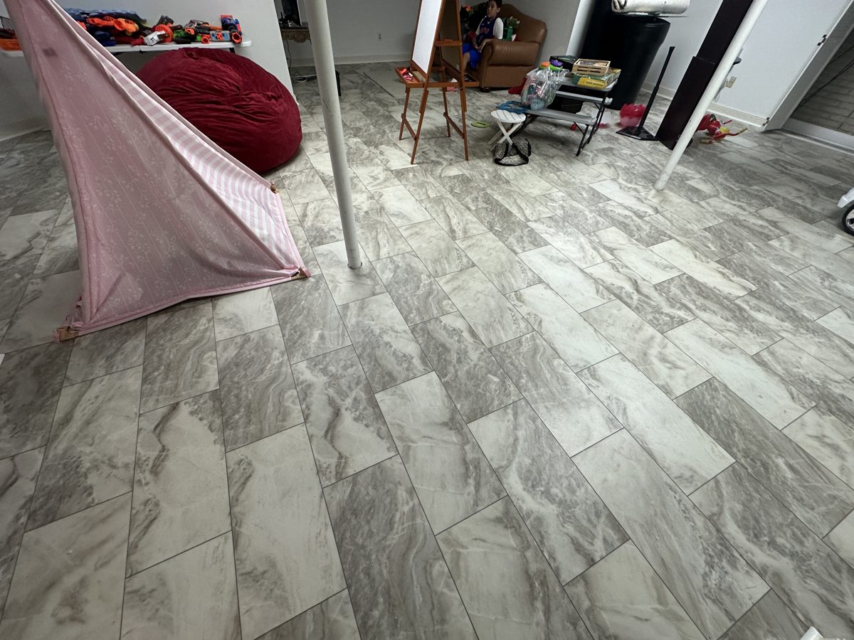 Basement play area with grey marble-look floor tiles laid in a staggered pattern