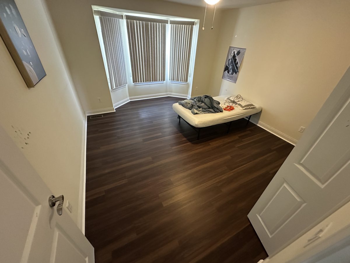Bedroom with dark brown wood-look plank flooring and a bay window