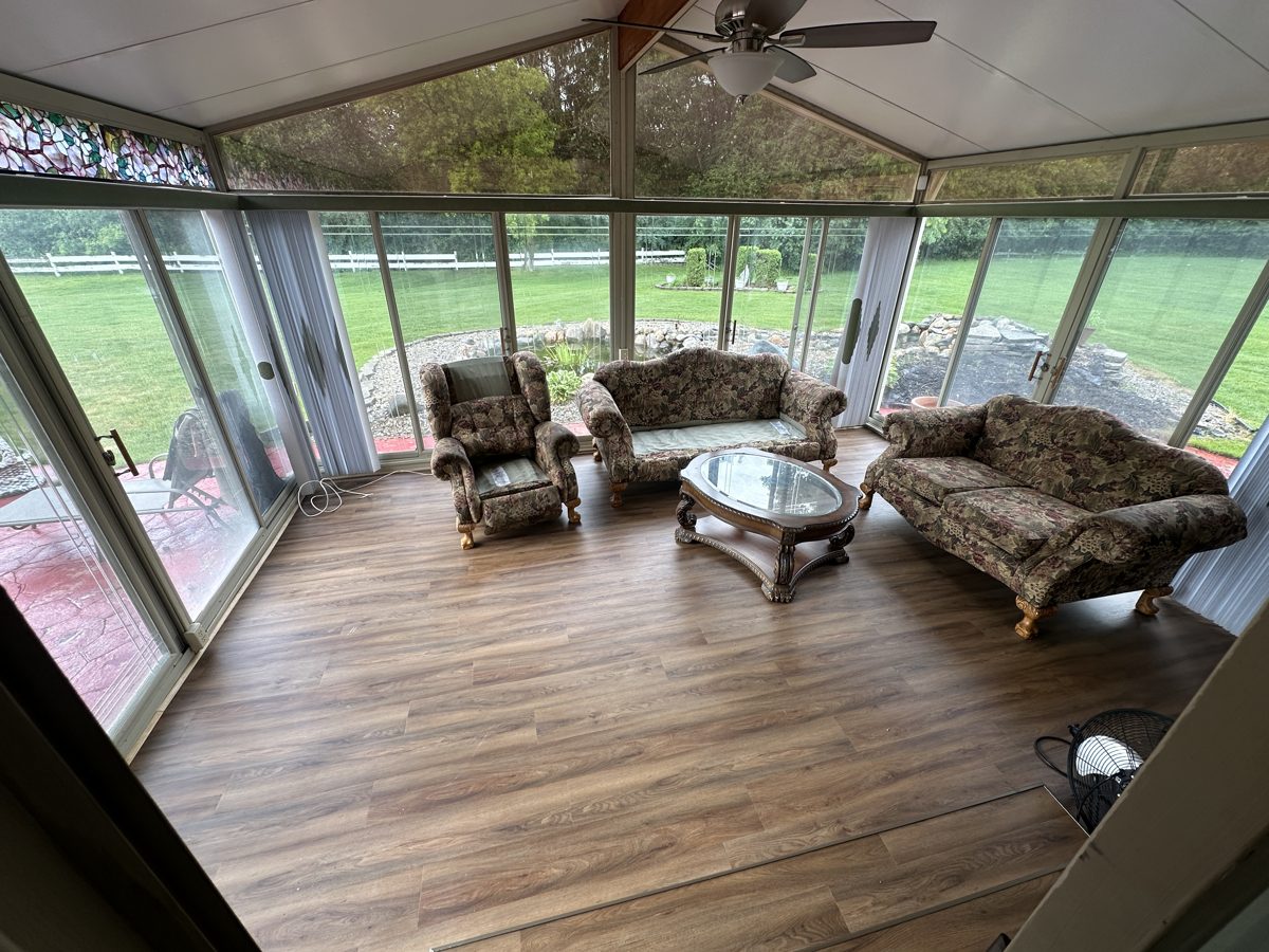 Sunroom with mid-brown wood-look plank flooring